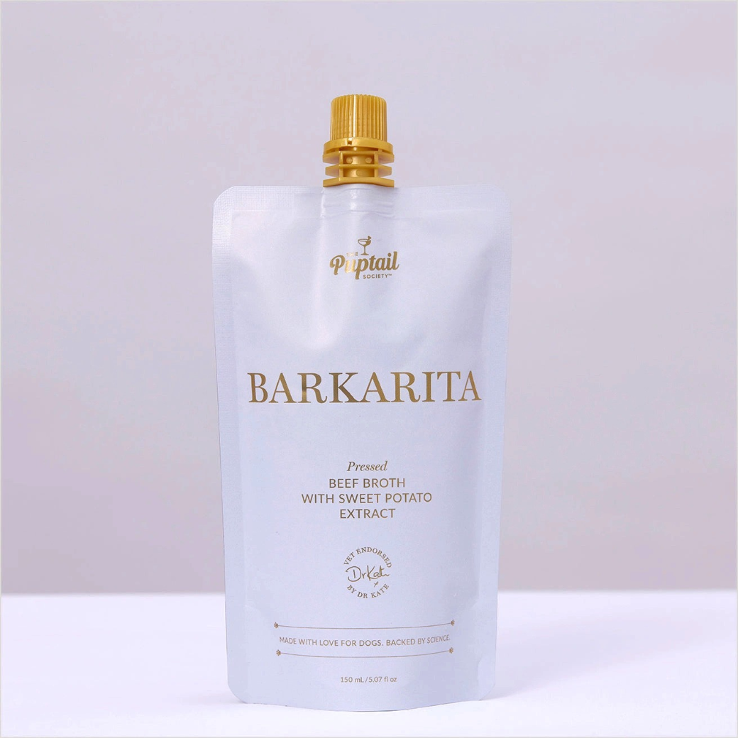 Coco & Pud - A 150 ml stand-up pouch of Barkarita Pressed Beef Broth with Sweet Potato Extract by Puptail Society, featuring a white pouch with gold lettering and a gold cap