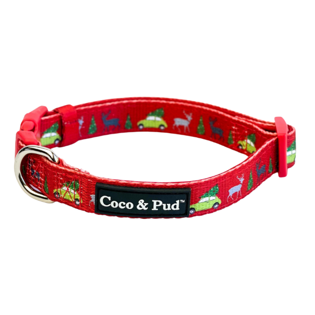 Coco & Pud - Deck The Paws, red dog collar with a festive Christmas pattern of green cars, pine trees, and white deer, featuring a black brand label that reads 'Coco & Pud