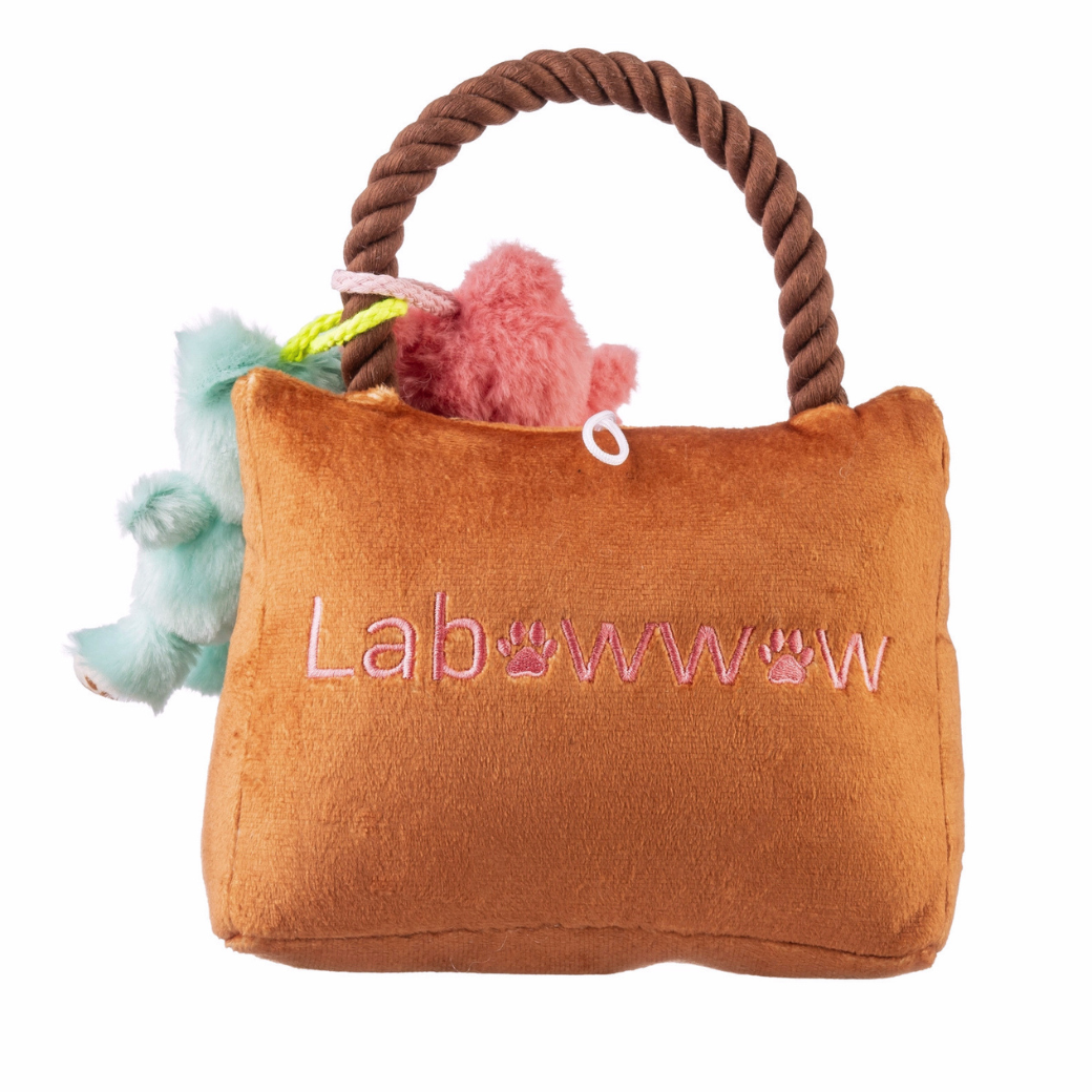 Coco & Pud Labowwow lush Dog Toy back - Haute Higgity DogA brown plush dog toy shaped like a handbag with a rope handle, pink embroidered 'Lab' and paw prints, and two small plush toys peeking out from the top.