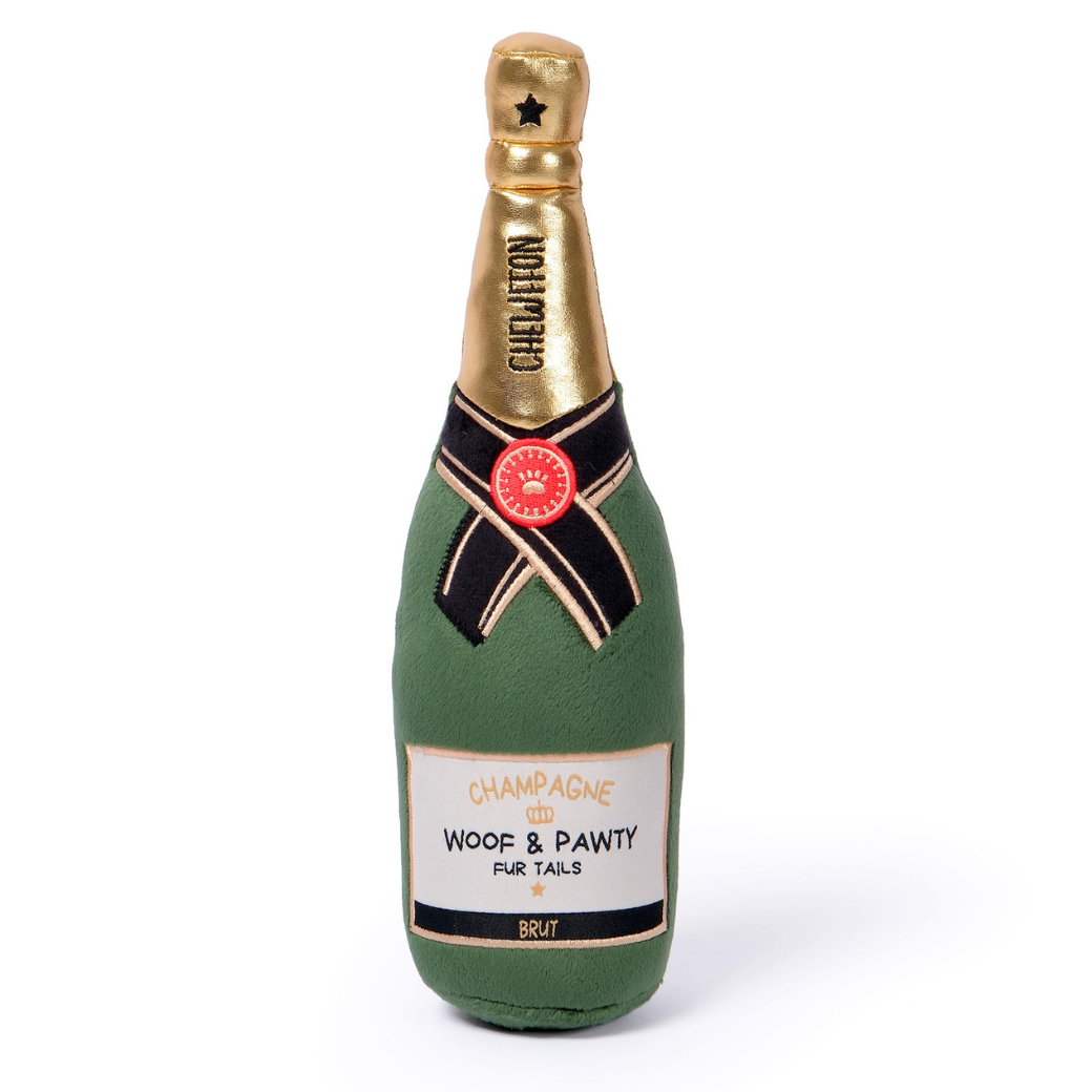 Woof & Pawty Champagne dog toy is a plush novelty champagne bottle toy with a green body, gold foil neck, and a black and gold patterned ribbon label, featuring the text 'CHAMPAGNE' and 'WOOF & PAWTY FUR TAILS' - Chewffon