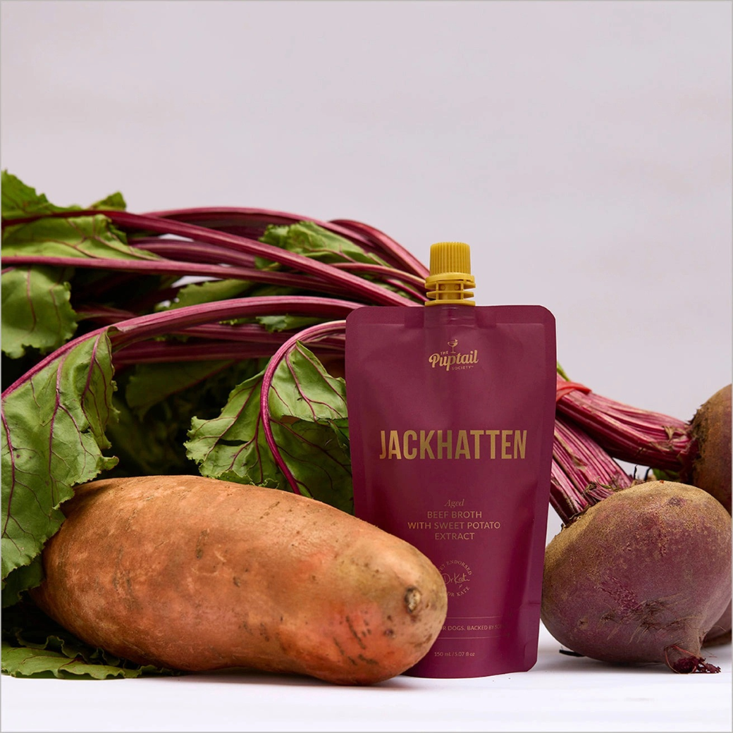 Coco & Pud - Jackhatten beef broth with sweet potato and beetroot tonic for dogs styled with fresh beet greens, a sweet potato, and beets  - Puptail Society