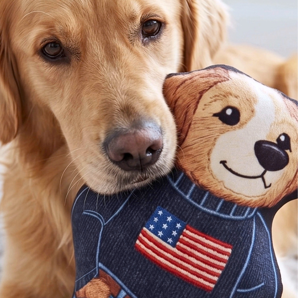 Coco & Pud - A golden retriever dog holds Ruff  Lauren Teddy dog toy against its neck. The toy is shaped like a dog's head wearing a dark blue sweater with an embroidered American flag patch - Haute Diggity Dog