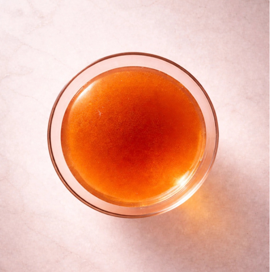 Coco & Pud - Barkarita   A top-down view of a clear glass bowl filled with pressed beef broth with sweet potato tonic