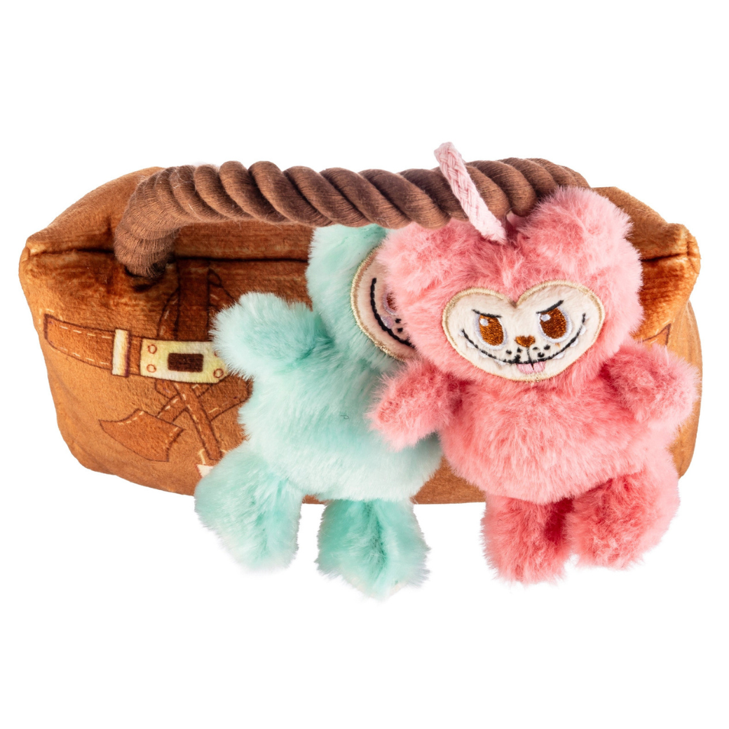 Coco & Pud Labowwow lush Dog Toy above view - Haute Higgity Dog. Two plush monkey toys, one pink and one mint green, sitting on a brown rope handle of a brown leather-like handbag.