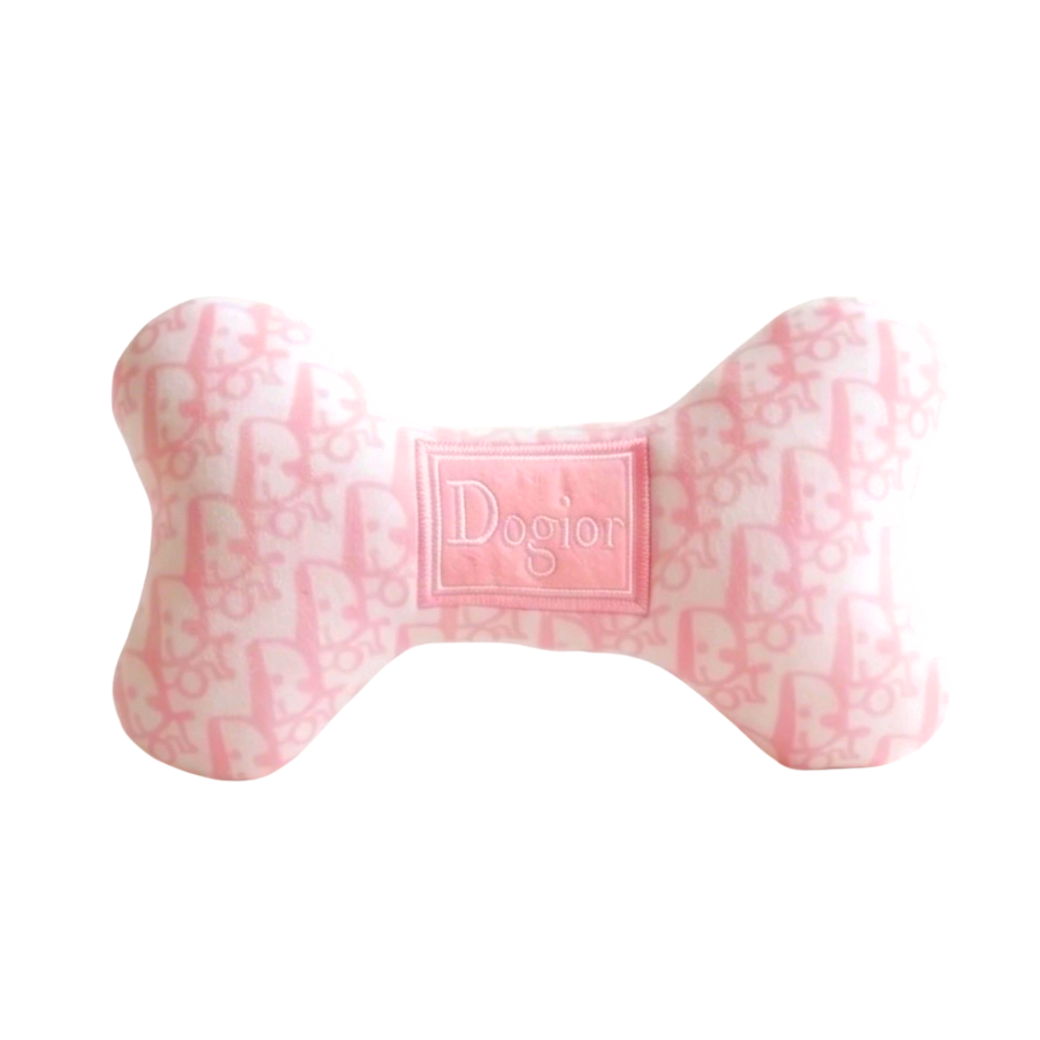 Coco & Pud A bone-shaped dog toy made of pink and white patterned fabric with a central embroidered patch reading 'Dogior' - Haute Diggity Dog