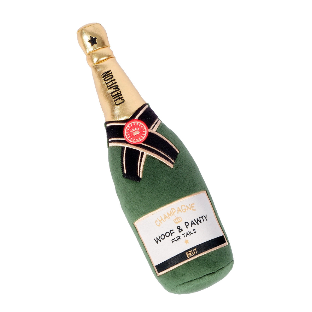 Coco & Pud - Woof & Pawty Champagne dog toy is a plush toy shaped like a champagne bottle, featuring green fabric, a gold neck, a black and white ribbon, and a label that reads 'Champagne - Woof & Pawty Fur Tails' - Chewffon