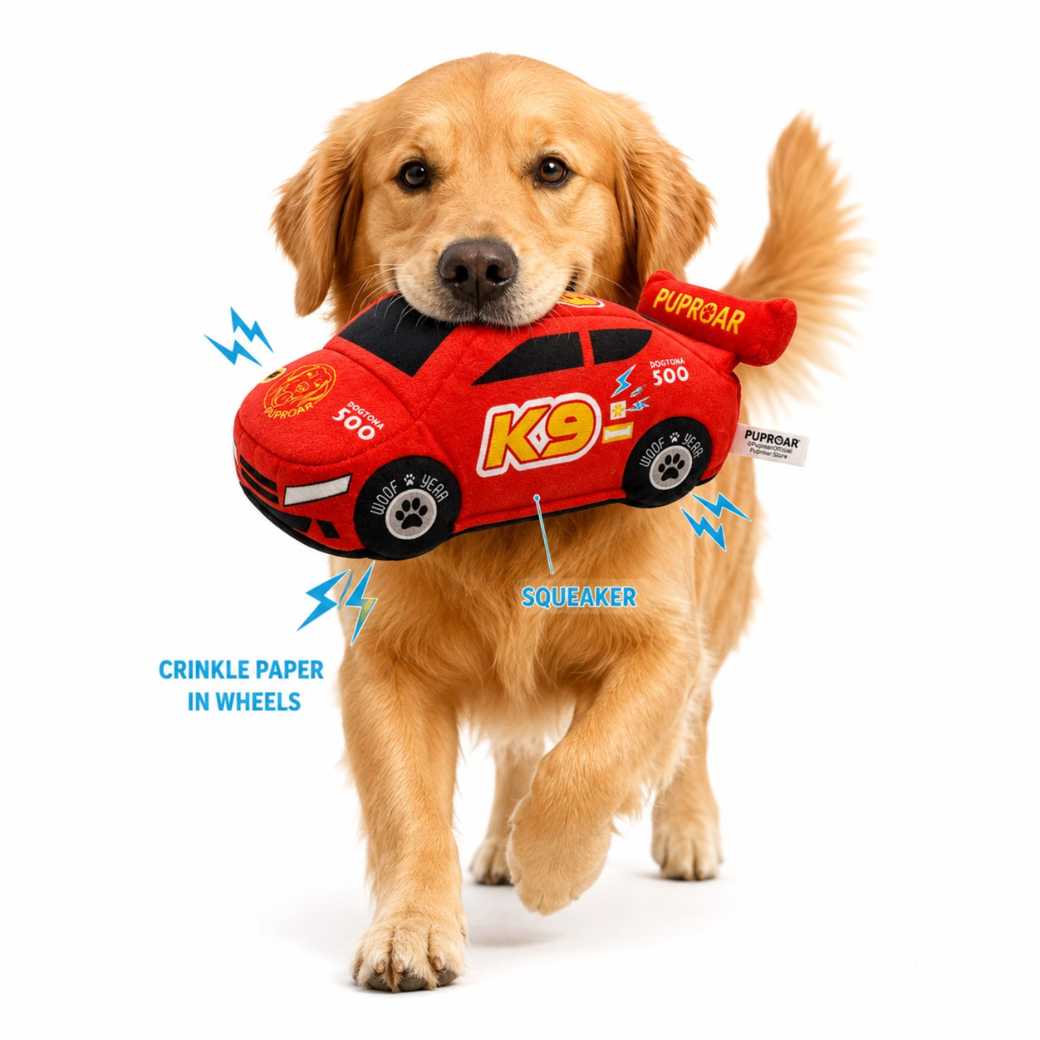 Coco & Pud - Stock Car Racing Car dog toy. A golden retriever dog is shown carrying a red plush racing car dog toy showing feature graphics. Puproar
