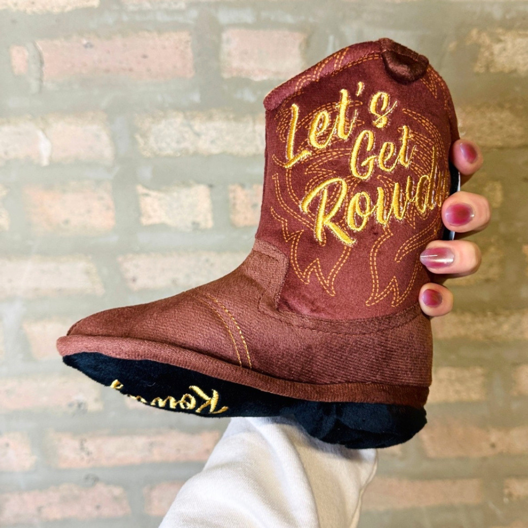 Coco & Pud Brown Cowboy Boot plush dog toy held against a rustic brick wall - Haute Diggity Dog