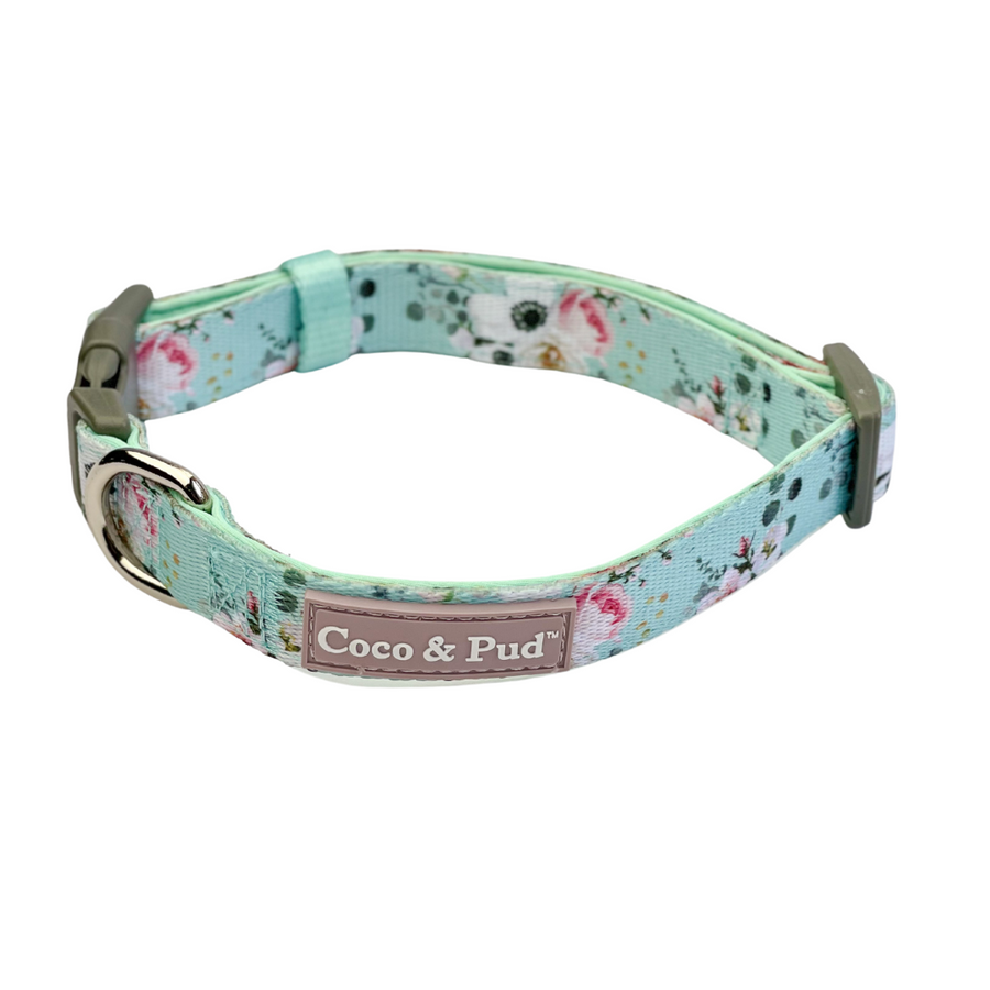 Coco & Pud French Azure Dog Collar -A floral dog collar with a mint green base, pink and white flowers, and small green leaves, featuring a silver-tone metal buckle and a brand patch that reads 'Coco & Pud'.
